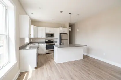 Representative stock photograph — renovated kitchen with quartz counters and vinyl plank flooring. Not a photograph of any asset in this panel.