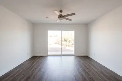 Representative stock photograph — vacant living area with vinyl plank flooring and a slider to the patio. Not a photograph of any asset in this panel.